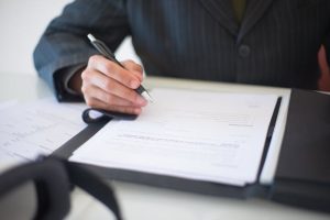difference between a will and a trust, image of man's arm and hand while signing a document